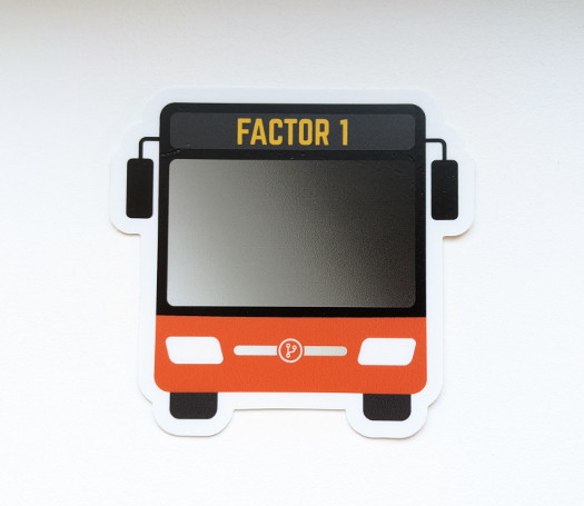 A bus-shaped sticker with the text 'Factor 1' near the top, and an orange accent color