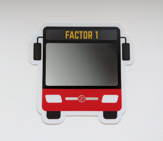 A bus-shaped sticker with the text 'Factor 1' near the top, and a red accent color