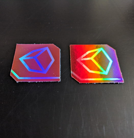 Two small holographic square stickers with cubes on them
