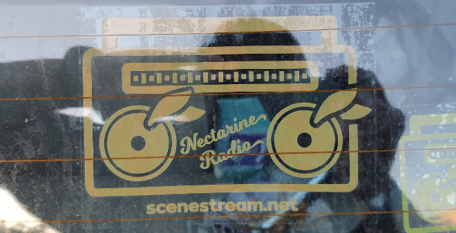 Orange 80-90’s boombox-themed Nectarine Radio window cling affixed to the inside of a car’s rear window